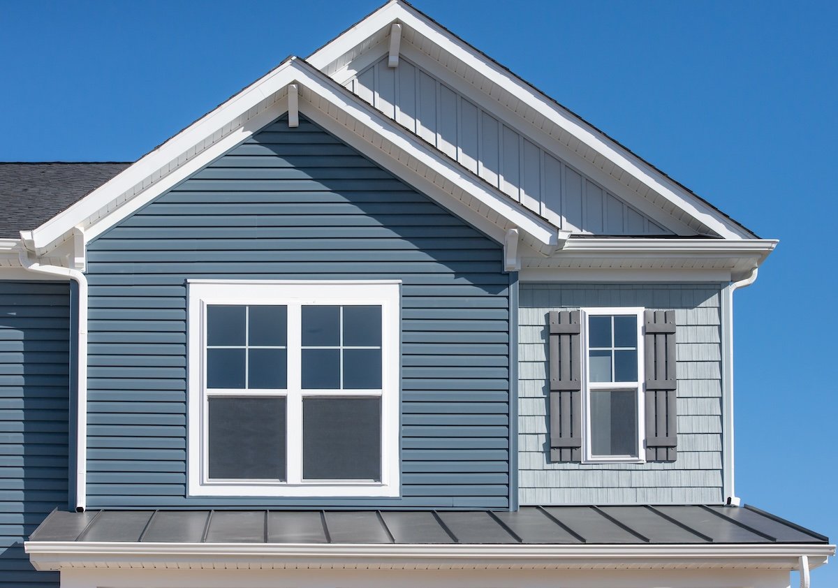 A close-up view of a house exterior with blue and light gray siding
