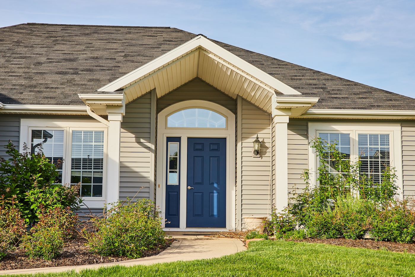 Gray siding house blue front door, arch entryway, slate gray checkered roof landscaping asset