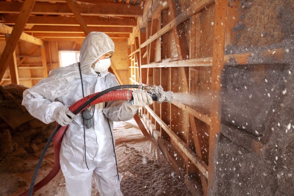 Spraying cellulose insulation on the wall.