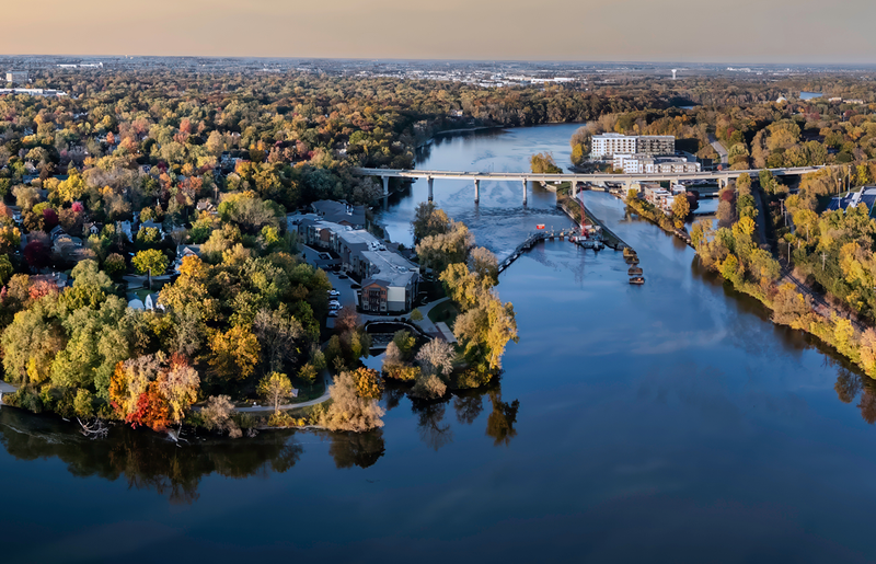 river winding through autumn trees, with a bridge, and waterfront buildings