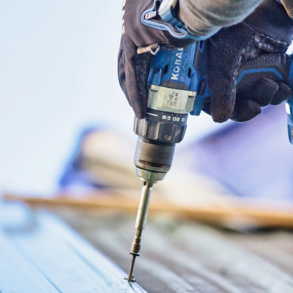 Close-up of a roofing professional using a power drill for a roofing company near me