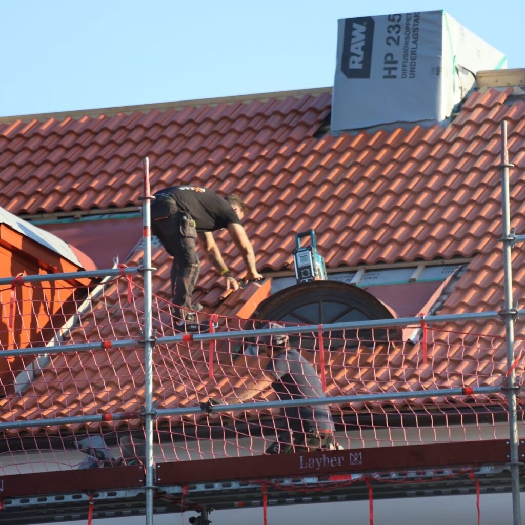 Roofing professional installing tile roofing with scaffolding for a trusted roofing company in Bolingbrook, IL