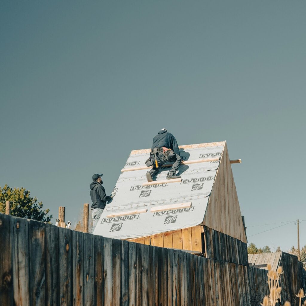 Roofing professionals installing underlayment on a steep roof for a roofing company near me